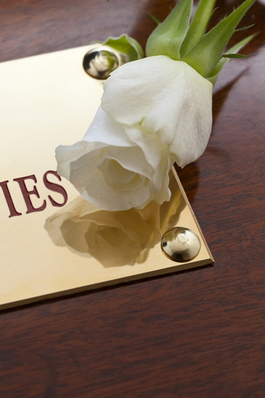 a white rose on top of a brass plaque that is on a wooden box