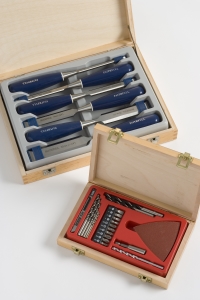 Wooden boxes with precision tools inside. The top box has blue-handled chisels, and the bottom displays assorted drill bits and a red triangular tool.