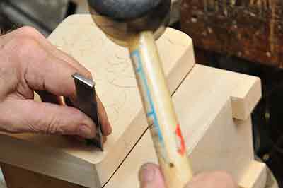 a hand with a rubber mallet etching a design onto a wooden box