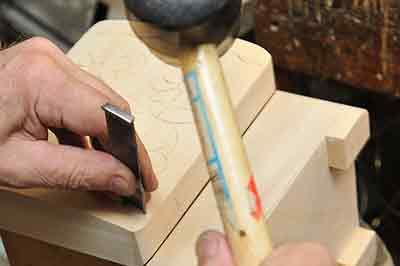 a hand with a rubber mallet etching a design onto a wooden box