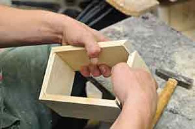 a man assembling a wooden box with his hands